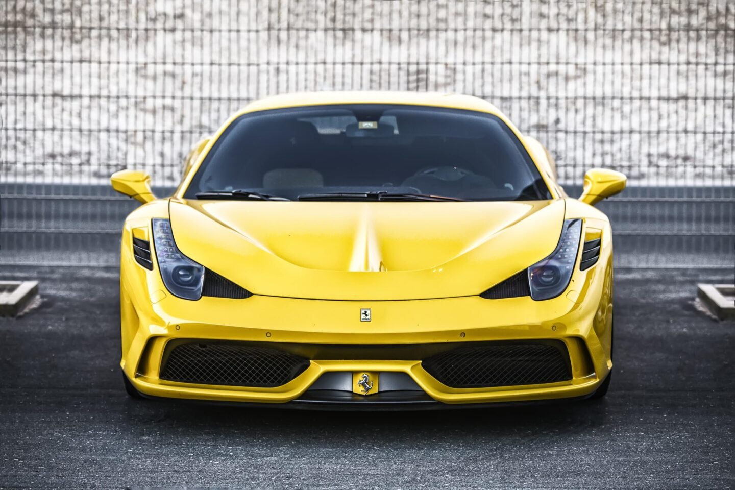 Front view of a yellow Ferrari Italia 458 Special Edition sports car parked on asphalt, photographed by Ahsan Ali Shahid.