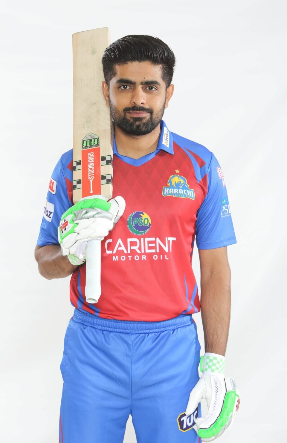 Professional studio headshot of Pakistani cricketer Babar Azam in his red and blue Karachi Kings PSL jersey, holding a cricket bat, by AHSANZ.