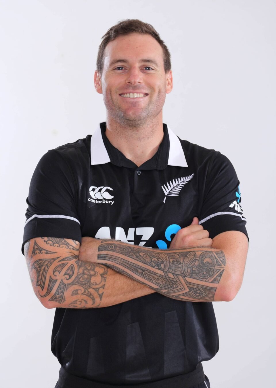 Professional studio portrait of New Zealand cricketer Matt Henry in the official black ANZ national kit, featuring prominent traditional tattoos on both arms, by AHSANZ.