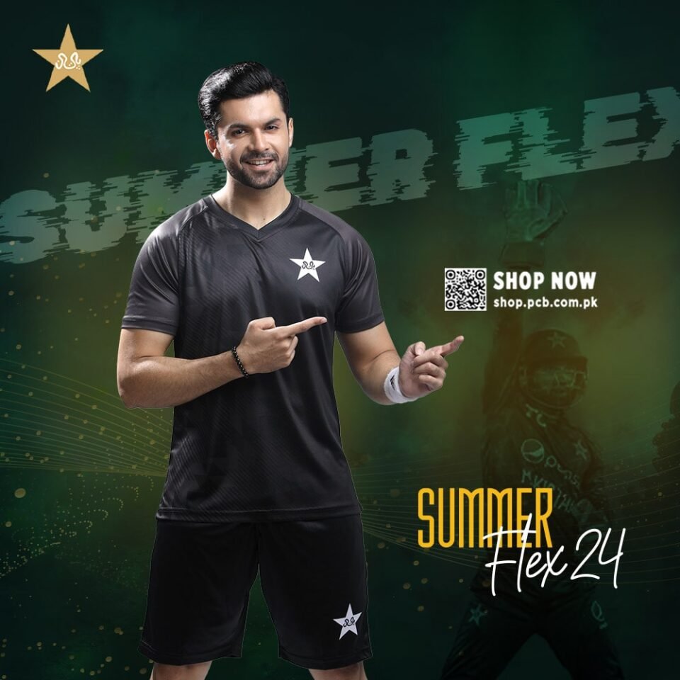 A sophisticated black training kit consisting of a V-neck shirt with a subtle stripe pattern and matching shorts, both featuring the white PCB star logo. The outfit is modeled by a smiling South Asian man with dark hair and a beard, who is pointing enthusiastically toward the right and left. The background is a dramatic, dark green and black with abstract graphics, and promotional text that reads "SUMMER FLEX 24" and "SHOP NOW https://www.google.com/search?q=shop.pcb.com.pk". Editorial fashion photography by AHSANZ.